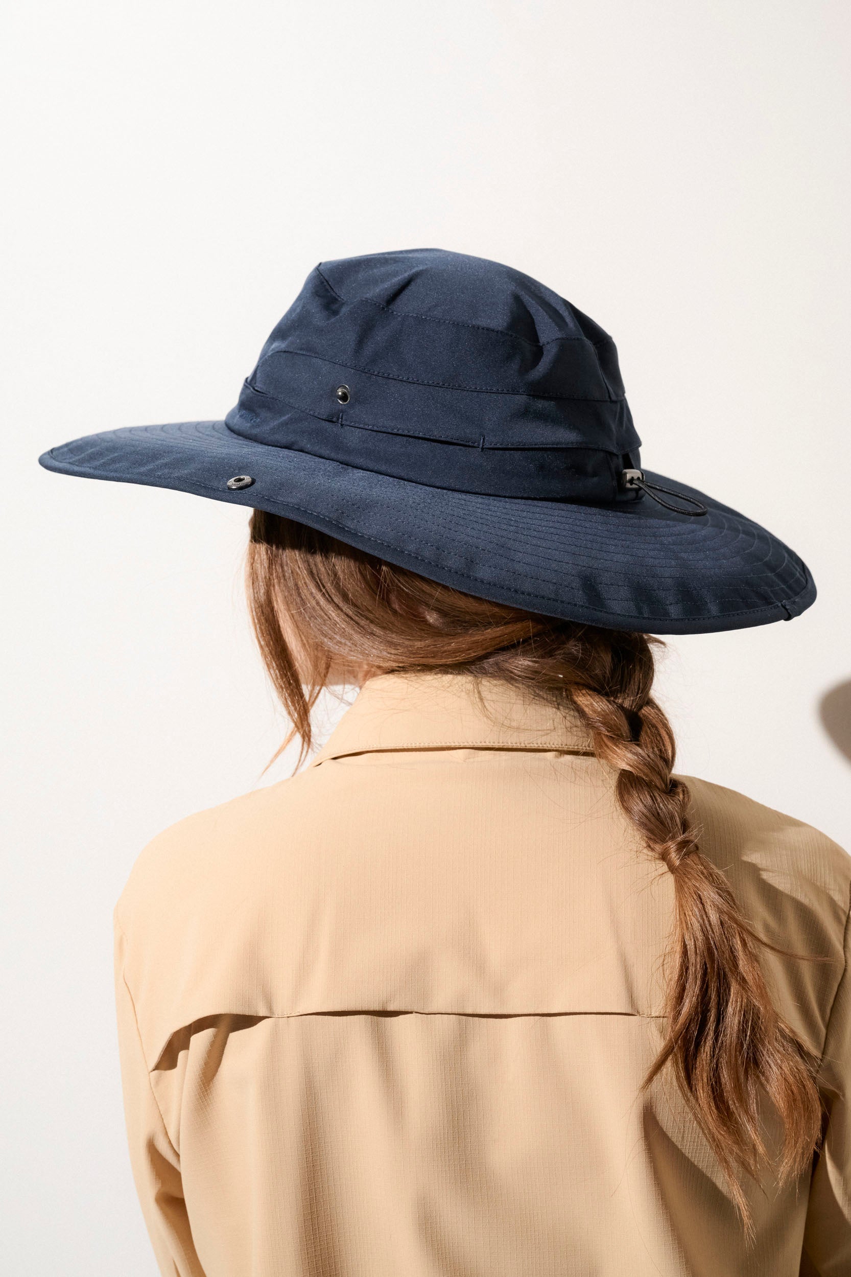 Chapeau anti-UV bleu sombre UPF50+ porté par une femme, idéal pour la randonnée et la protection solaire.