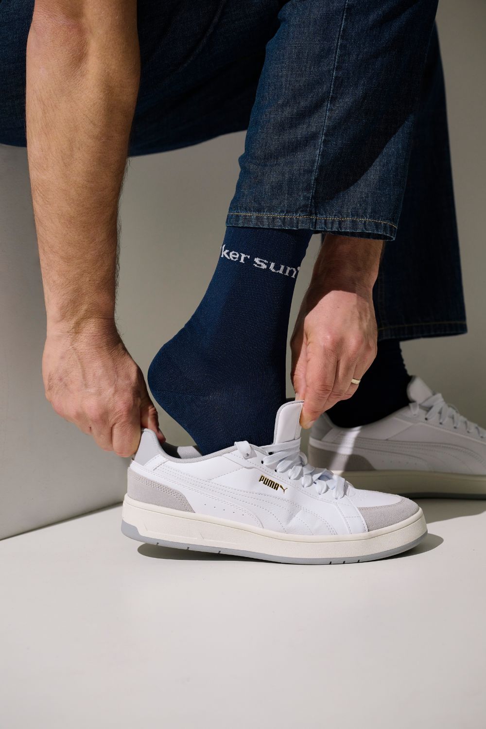 Chaussettes anti-UV - Mojave, couleur bleu marine, portées par un homme en train de mettre des chaussures blanches.