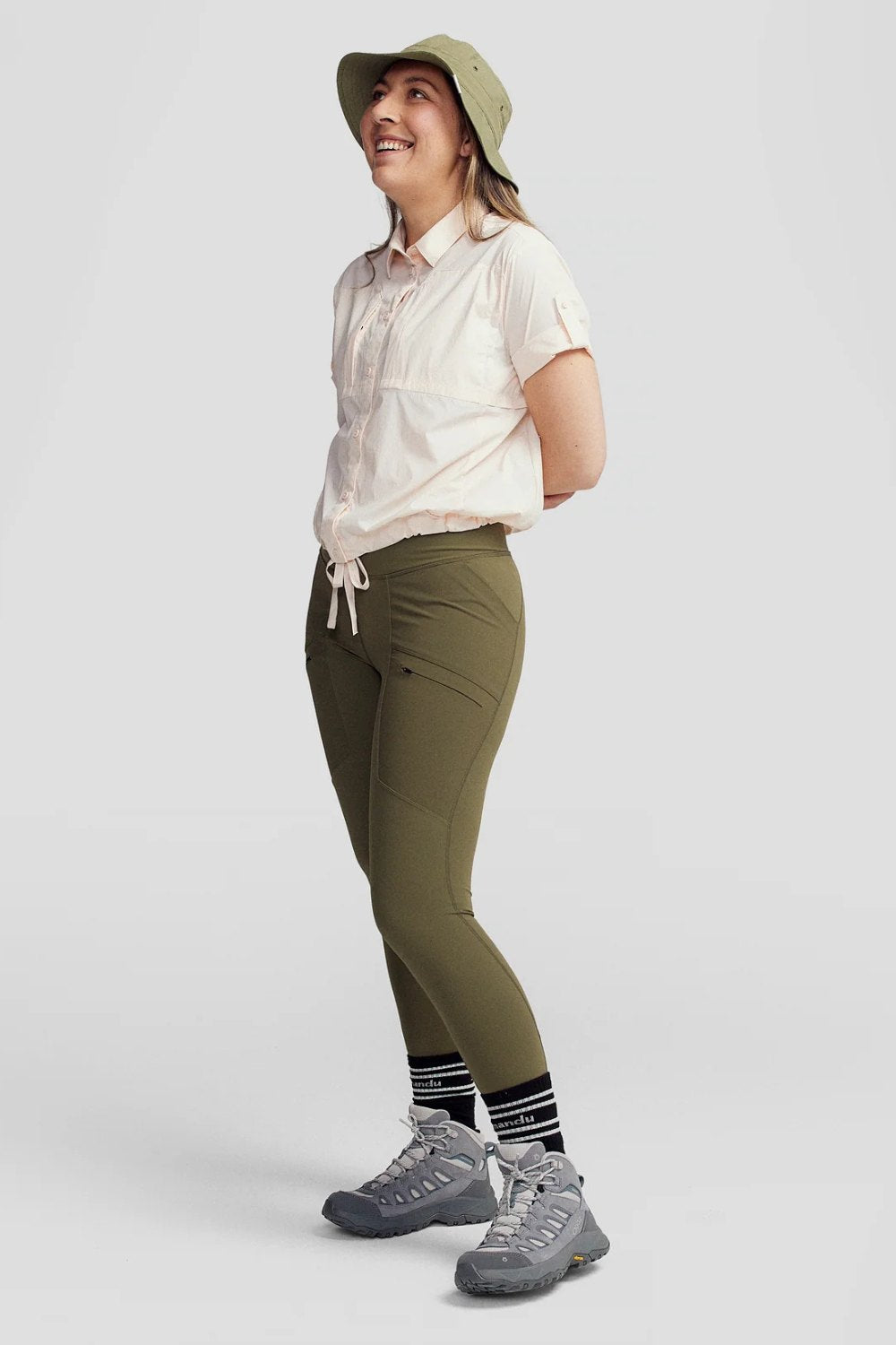 Femme souriante en chemise anti-UV Ridge légère et pantalon de randonnée, idéale pour les activités en plein air.