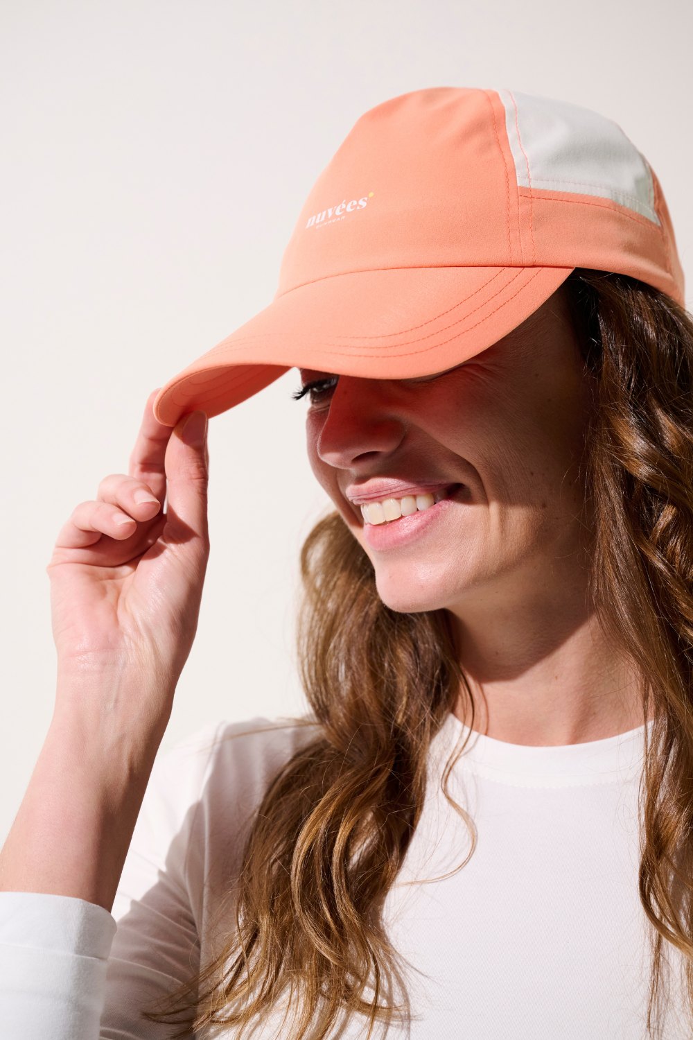 Femme souriante portant une casquette anti-UV orange, idéale pour les activités de plein air.