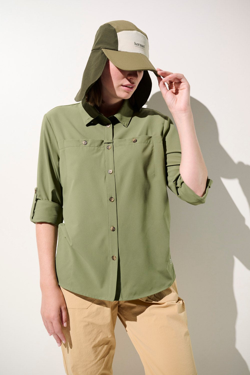 Femme portant une chemise anti-UV vert olive et une casquette avec protection solaire UPF 50+, idéale pour activités extérieures.