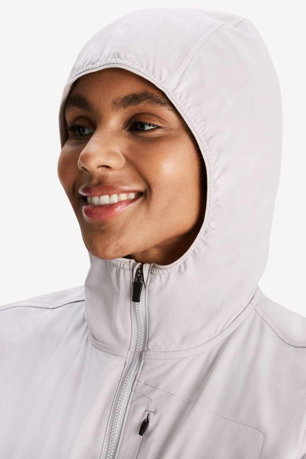 Femme sourire portant une veste anti-UV blanche à capuche, légère et respirante, offrant protection UPF 50+.