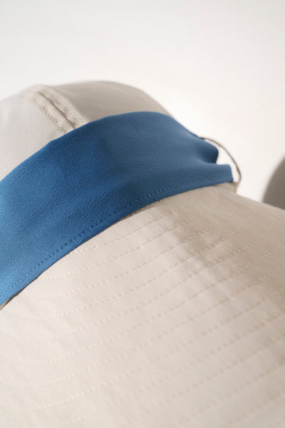 Casquette légère beige avec visière bleue, protection anti-UV UPF50+, idéale pour sorties en plein air.