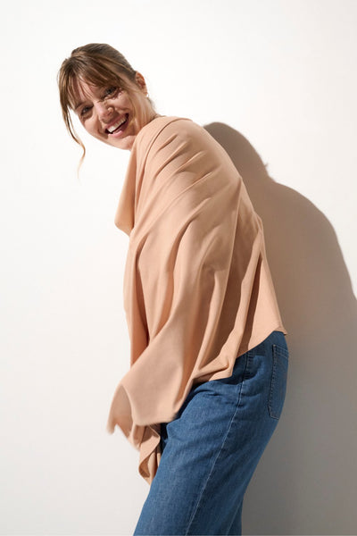 Femme portant une étole anti-UV beige UPF50+, idéale pour une protection solaire à la plage ou en ville.