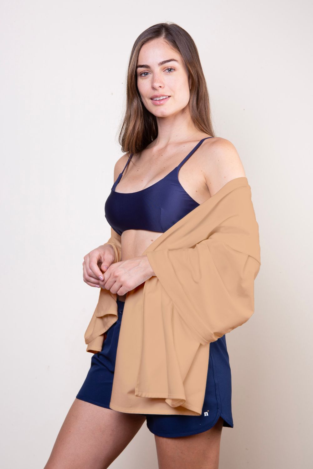 Femme portant une étole anti-UV beige UPF50+, idéale pour une protection solaire à la plage.