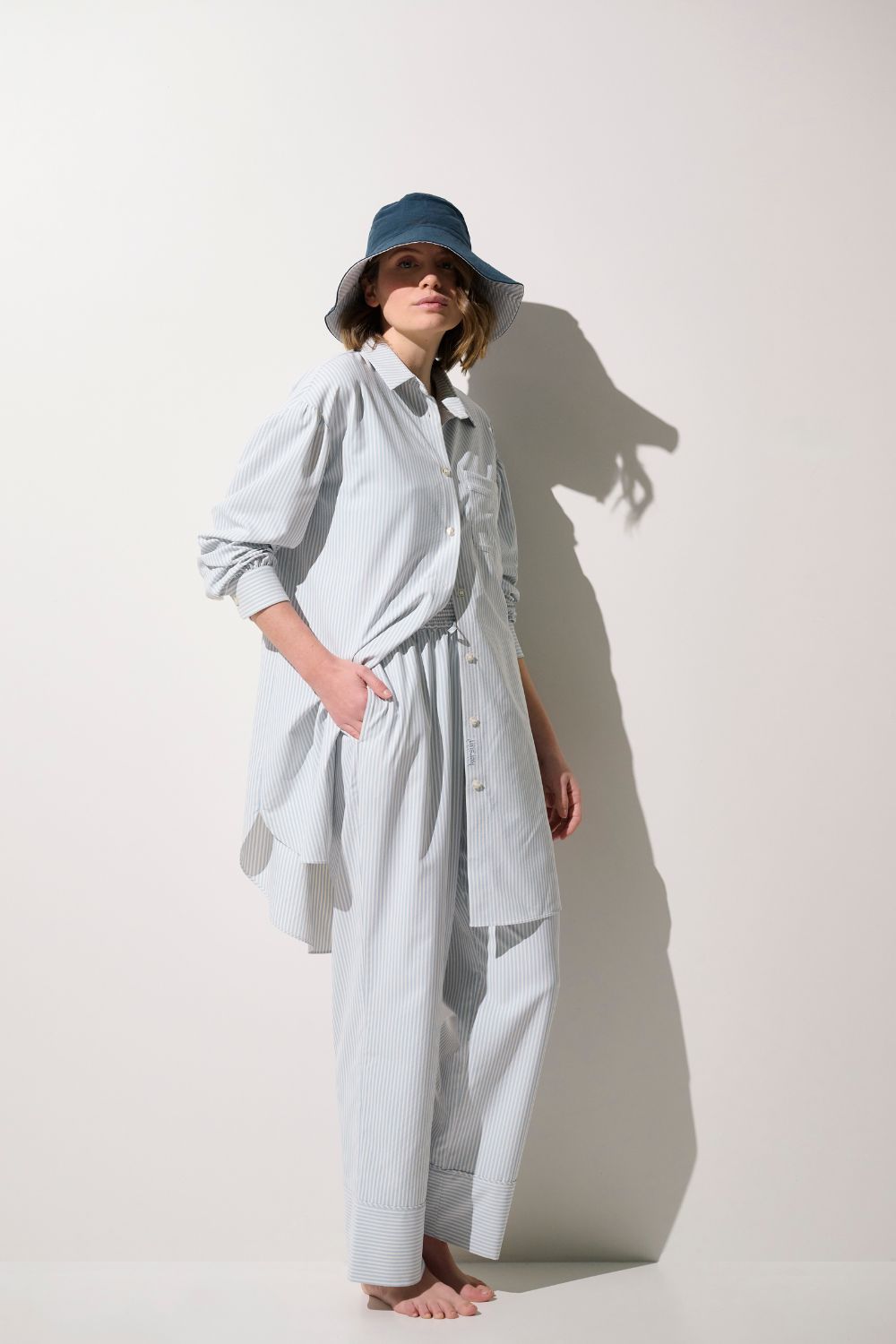 Chemise longue anti-UV - Sylt, légère et élégante, portée par une femme avec un chapeau, pour protection solaire.