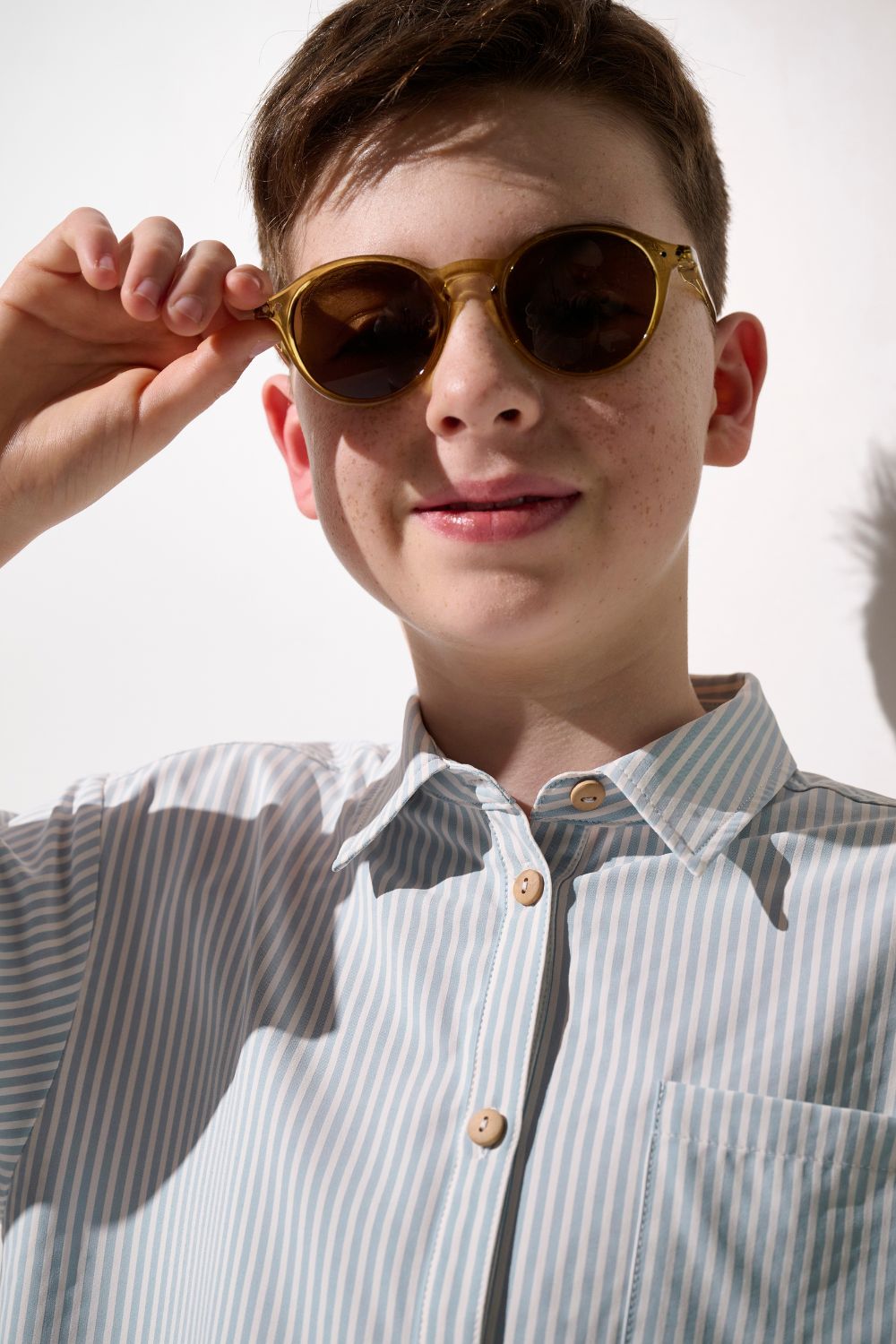 Enfant portant une chemise anti-UV - Sylt à rayures, lunettes de soleil, pour une protection solaire stylée.