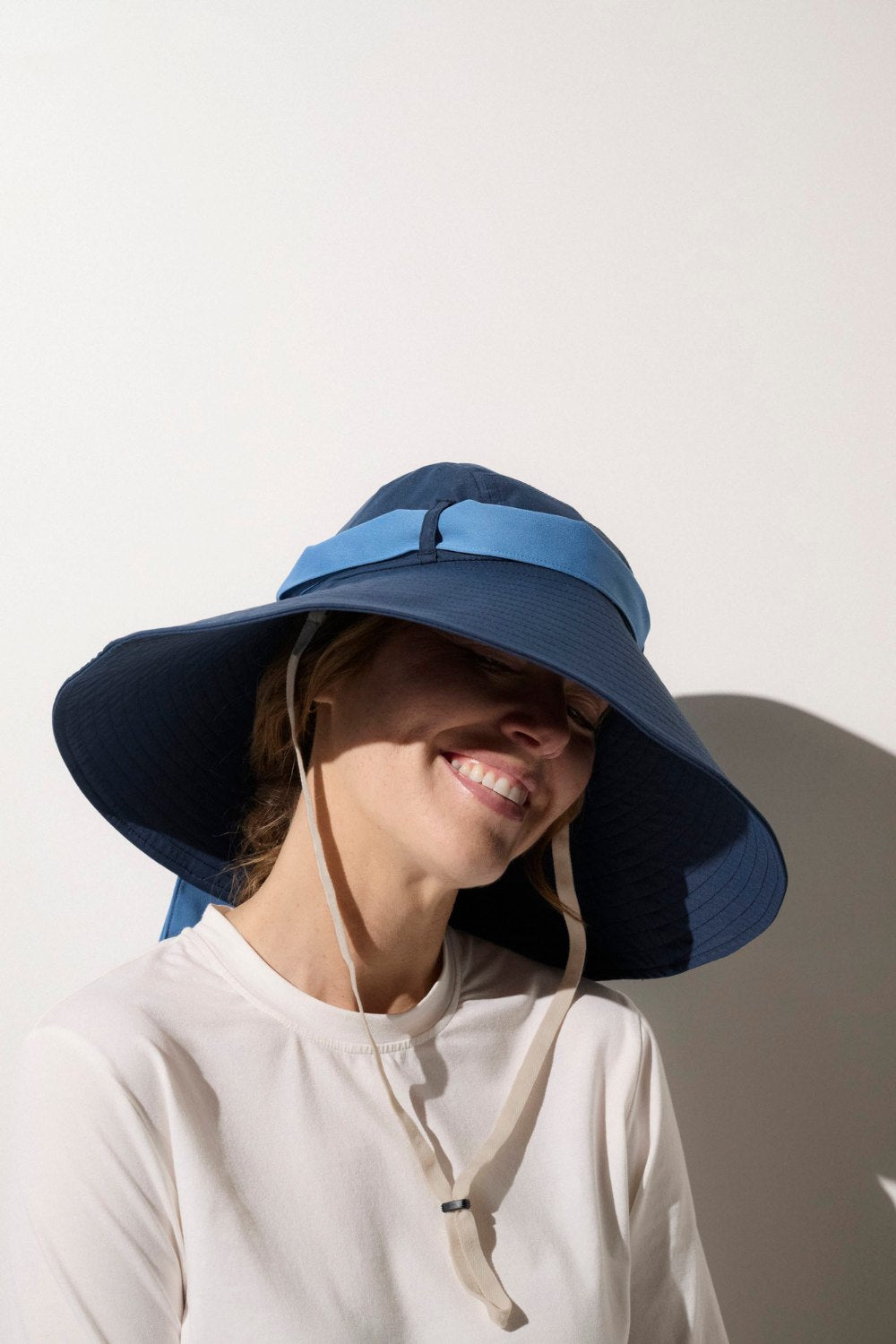 Femme portant un t-shirt anti-UV à manches longues et un chapeau large pour protection solaire.
