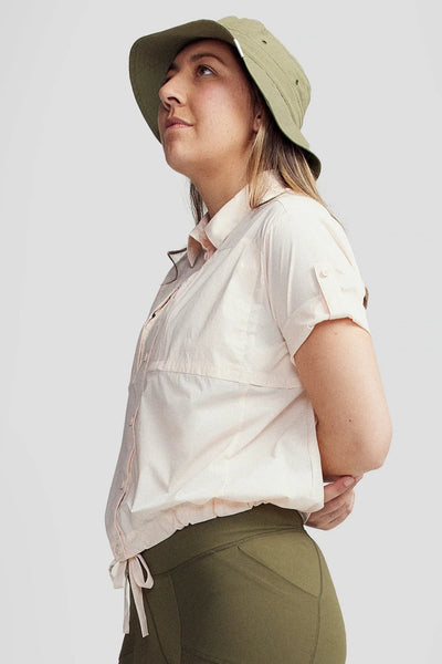 Chemise anti-UV - Ridge, coupe boxy rose pour femme, UPF 50+, portée avec un chapeau dans un cadre décontracté.