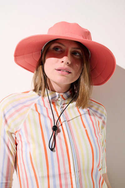 Chapeau de bain anti-UV - Galápagos rose, porté par une femme, idéal pour protection solaire lors d'activités extérieures.