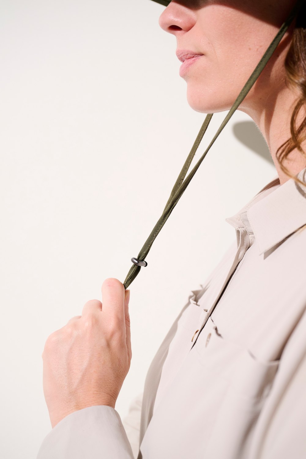 Chapeau anti-UV - Sequoia, femme ajustant la lanière, élégance et confort pour une protection solaire efficace.