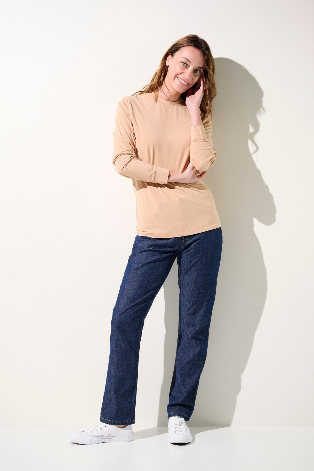 Femme portant un T-shirt anti-UV beige à manches longues et un jean anti-UV, légers et confortables, offrant une protection solaire UPF 50+.