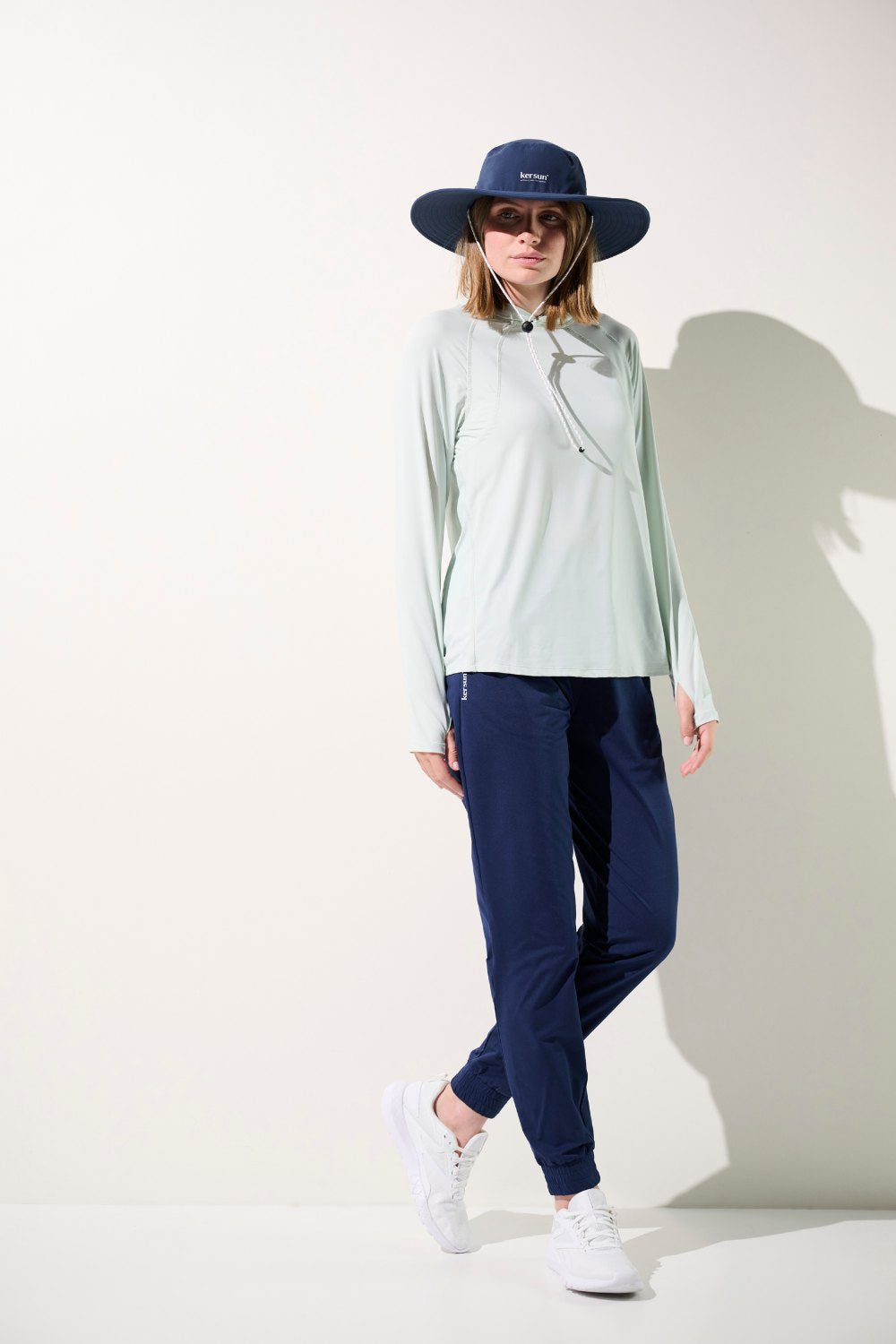 Femme portant un chapeau anti-UV - Oasis, haut léger UPF 50+ et pantalon confortable, idéale pour activités extérieures.