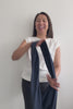 Femme souriante portant un t-shirt léger, tenant un wrap anti-UV noir Capri, parfait pour le soleil.